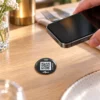 Smartphone approché d'un IZI TAG collé sur une table, lecture NFC sans application