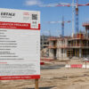 Panneau de chantier connecté NFC et QR code devant un chantier de construction