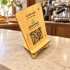 Chevalet bois NFC IZIGUEST — logo ou visuel fourni — en situation, QR Code transparent imprimé sur la face en bois.